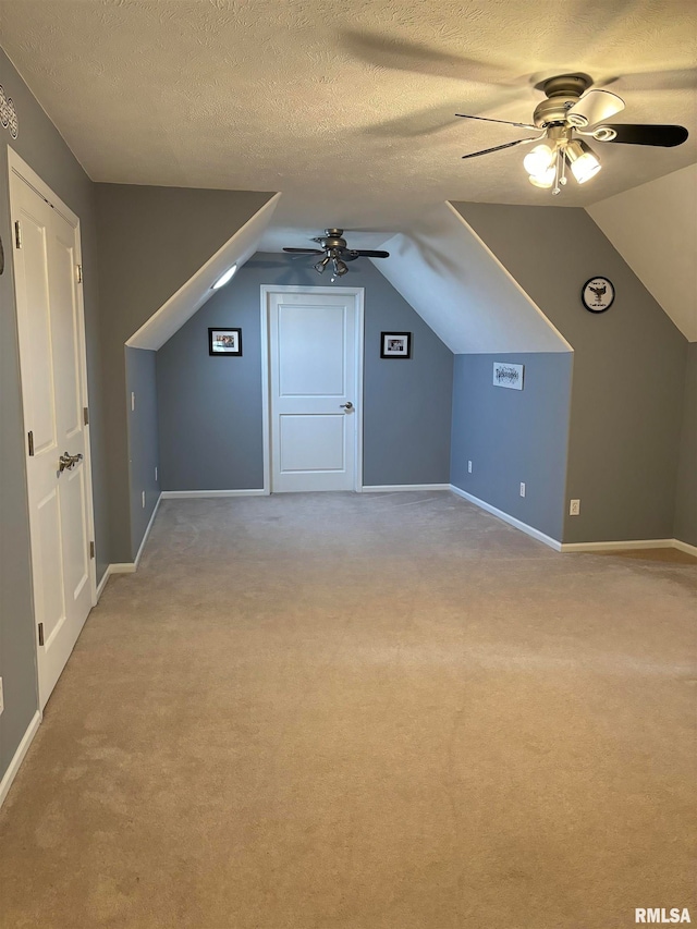 bonus room featuring a textured ceiling, light carpet, and ceiling fan