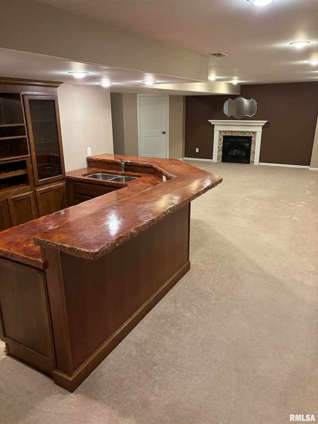 bar featuring dark stone countertops, light carpet, and sink