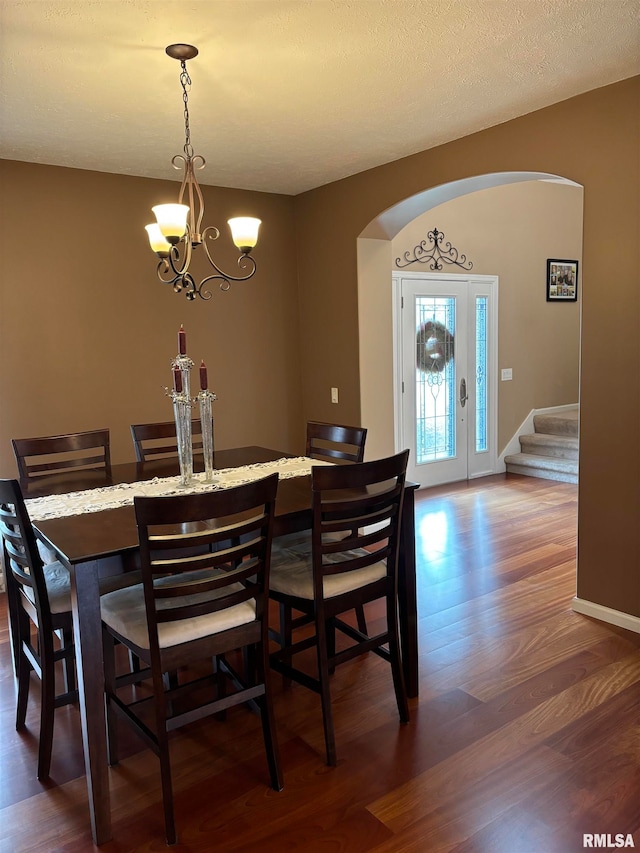 dining room featuring dark wood-type flooring, a textured ceiling, and an inviting chandelier