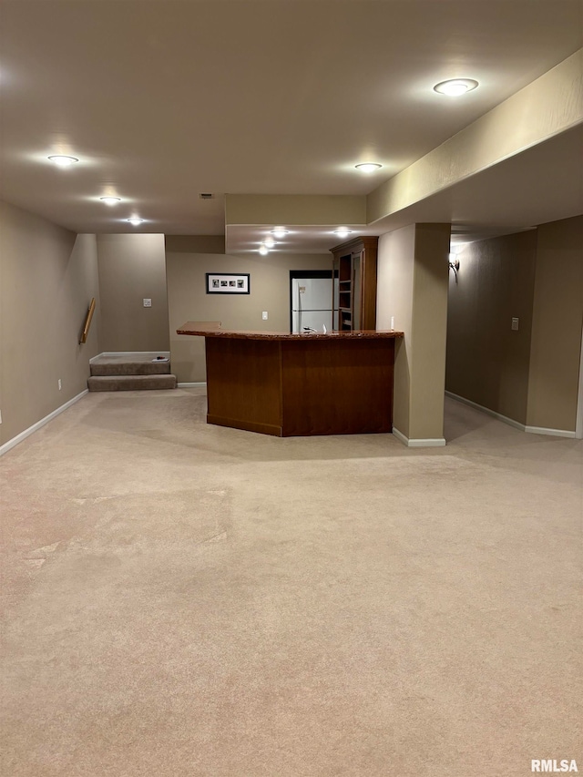 basement with bar area, carpet floors, and white fridge