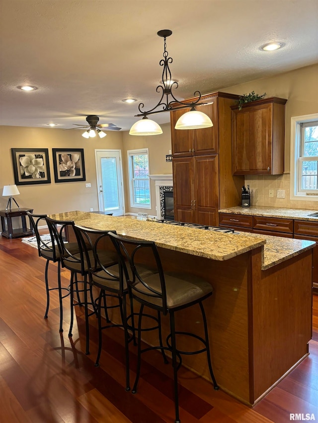 kitchen featuring dark wood-type flooring, a breakfast bar area, pendant lighting, and a kitchen island