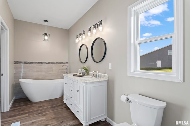 bathroom with vanity, hardwood / wood-style flooring, tile walls, toilet, and a bathing tub