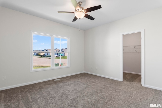 unfurnished bedroom with a spacious closet, ceiling fan, carpet floors, and a closet