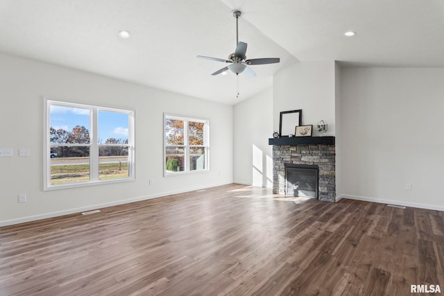 unfurnished living room with ceiling fan, hardwood / wood-style flooring, lofted ceiling, and a stone fireplace