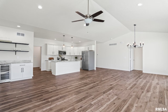 unfurnished living room with ceiling fan with notable chandelier, high vaulted ceiling, dark hardwood / wood-style floors, and wine cooler