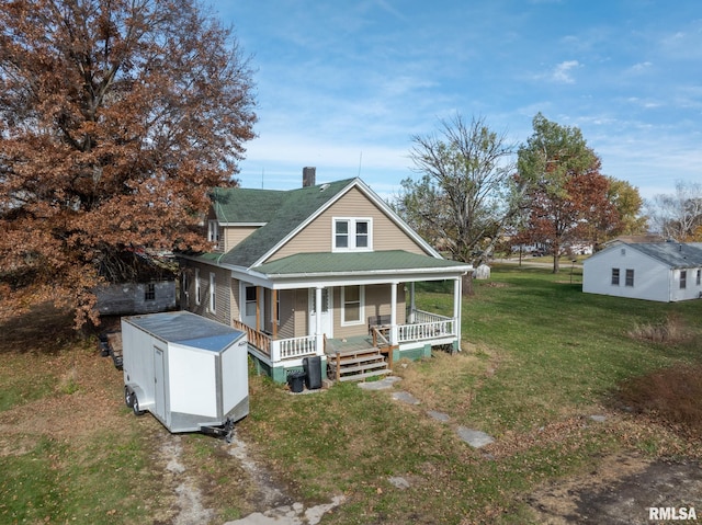 back of property with covered porch, a lawn, and a storage shed