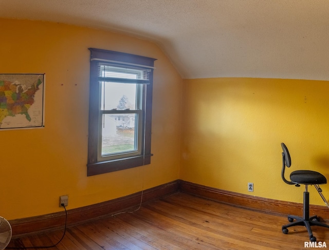 additional living space featuring a textured ceiling, vaulted ceiling, and hardwood / wood-style flooring