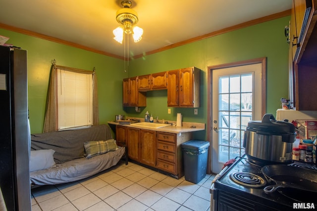 kitchen featuring sink, light tile patterned floors, crown molding, ceiling fan, and stainless steel fridge