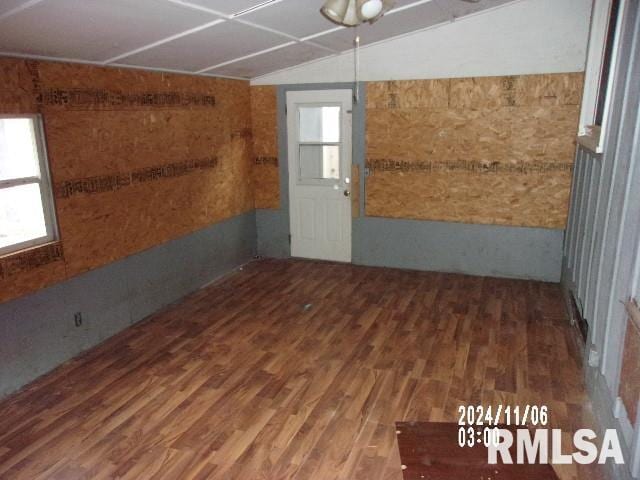 spare room with dark hardwood / wood-style floors, vaulted ceiling, and a healthy amount of sunlight