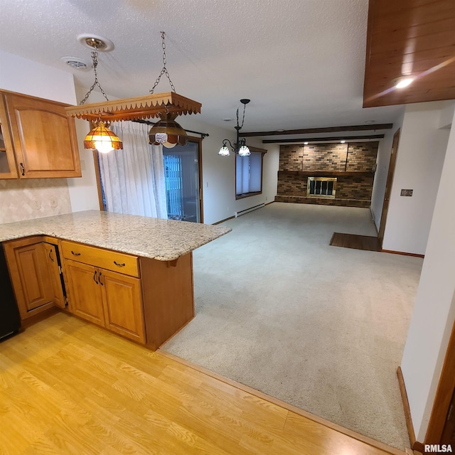 kitchen featuring decorative light fixtures, light wood-type flooring, kitchen peninsula, and a textured ceiling