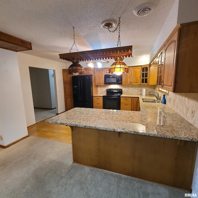 kitchen featuring pendant lighting, black appliances, sink, a textured ceiling, and kitchen peninsula