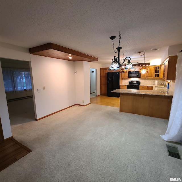 kitchen featuring kitchen peninsula, a textured ceiling, sink, black appliances, and pendant lighting