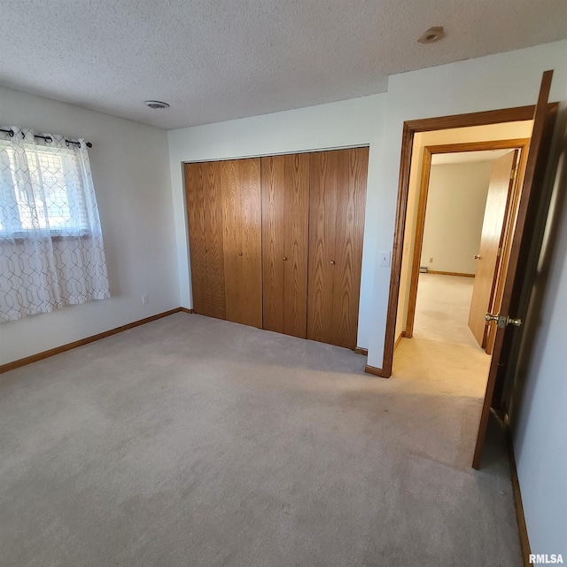 unfurnished bedroom featuring a textured ceiling, light colored carpet, and a closet