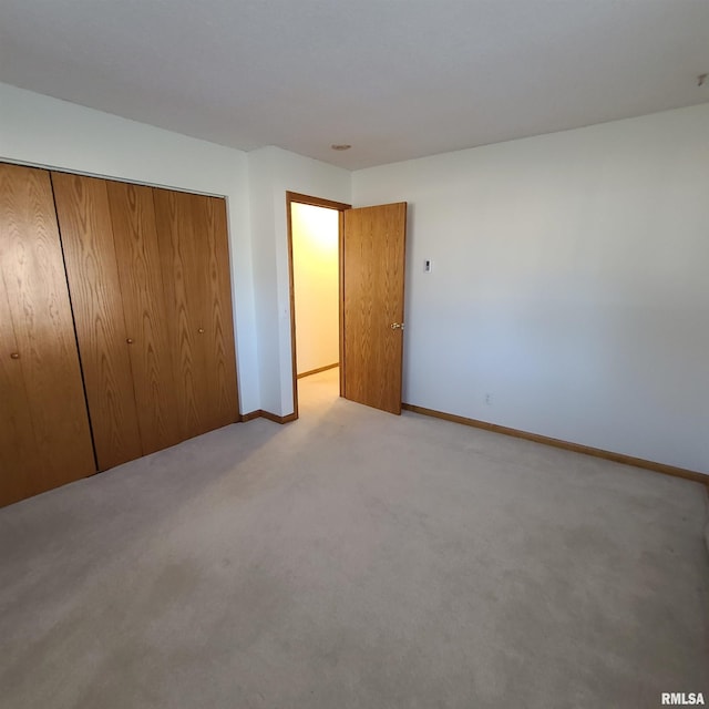 unfurnished bedroom with light carpet and a closet