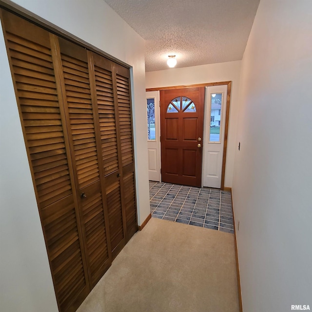 foyer with dark carpet and a textured ceiling