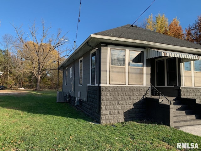 view of side of home featuring a lawn and central AC