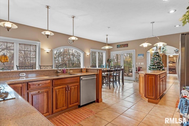 kitchen featuring pendant lighting, a center island, sink, stainless steel dishwasher, and light tile patterned floors