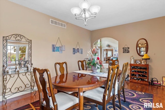 dining space with dark wood-type flooring and a notable chandelier