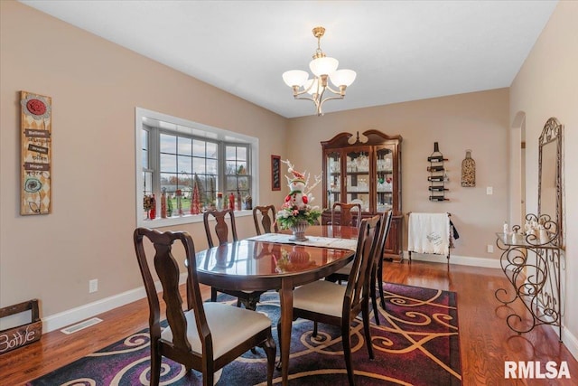 dining area featuring wood-type flooring and a notable chandelier