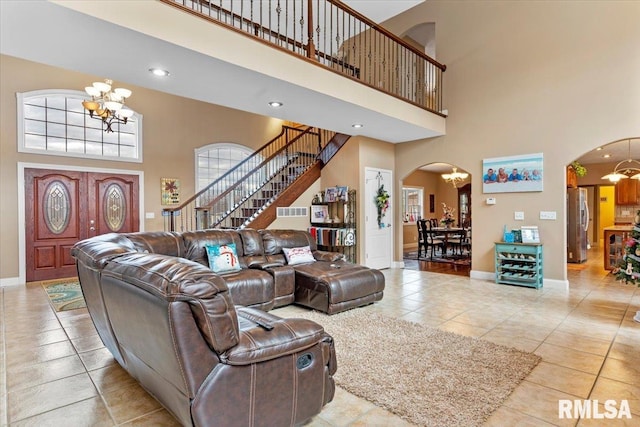 living room featuring a chandelier, a towering ceiling, and light tile patterned flooring