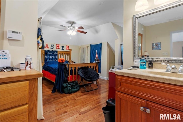 bedroom featuring light hardwood / wood-style floors, ceiling fan, and sink