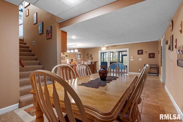 tiled dining room with ceiling fan with notable chandelier and a textured ceiling