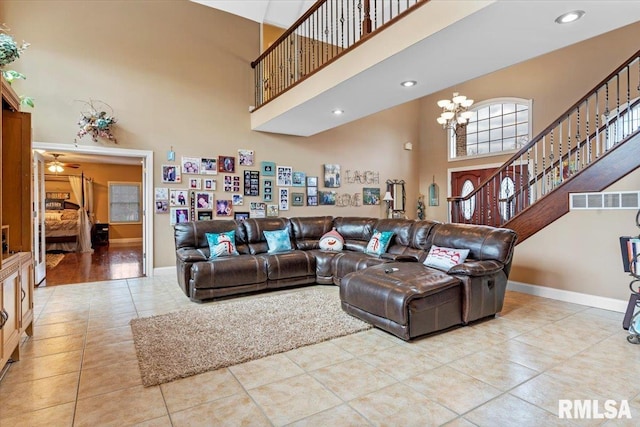 living room featuring ceiling fan with notable chandelier, a towering ceiling, and light tile patterned floors