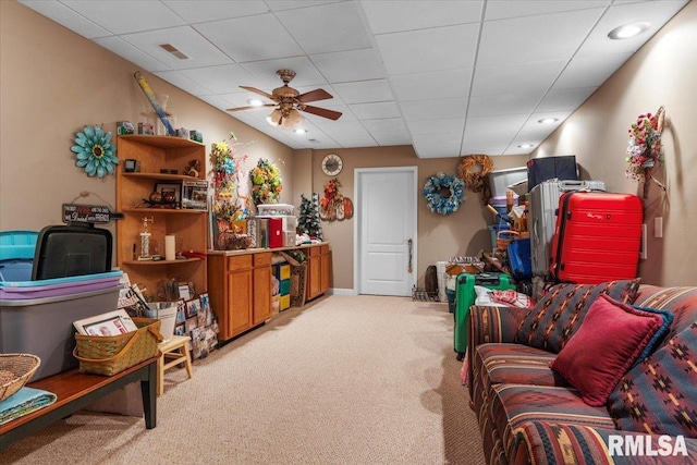 sitting room with ceiling fan, a drop ceiling, and light colored carpet