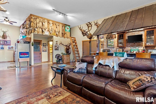 living room with wood-type flooring, a textured ceiling, track lighting, and ceiling fan