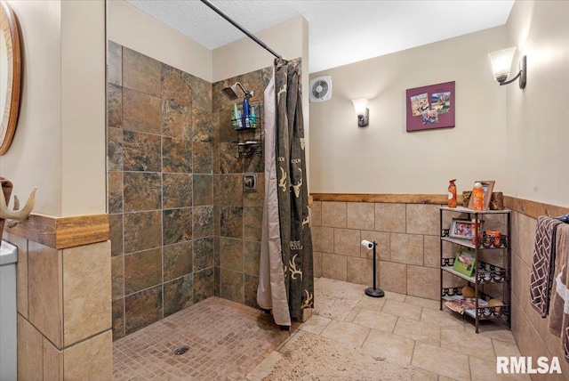 bathroom featuring curtained shower, a textured ceiling, and tile walls