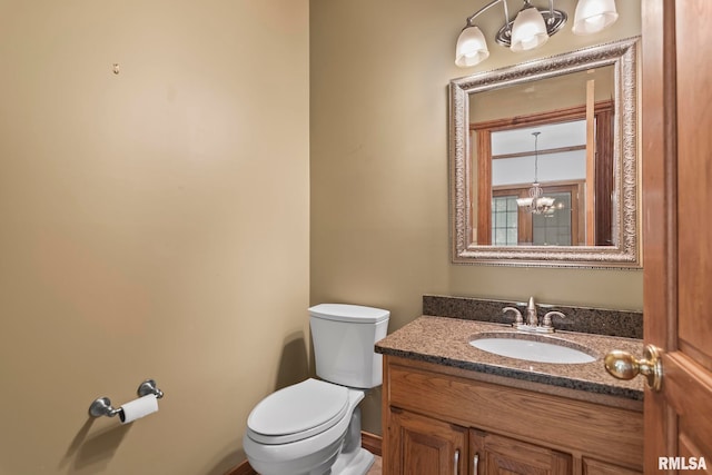 bathroom with toilet, a chandelier, and vanity