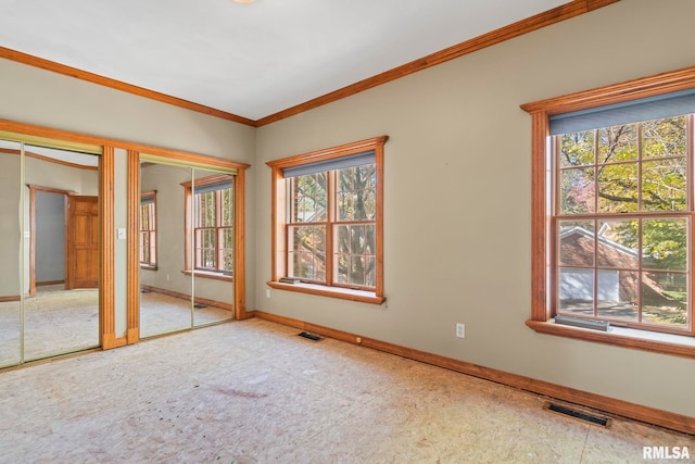 unfurnished bedroom featuring multiple closets, crown molding, and multiple windows