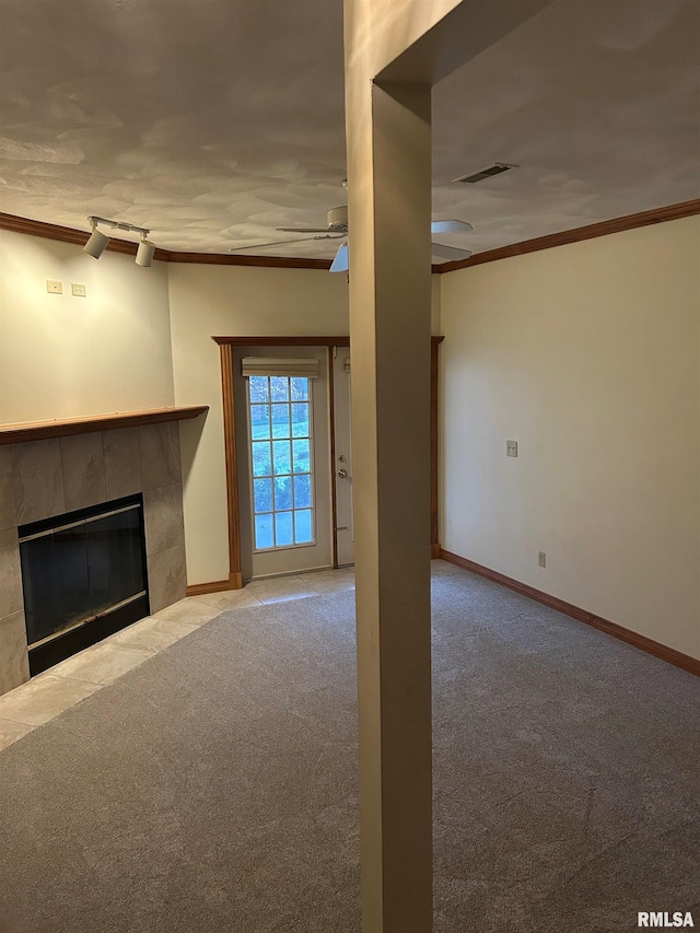 unfurnished living room featuring ceiling fan, light colored carpet, crown molding, and a fireplace