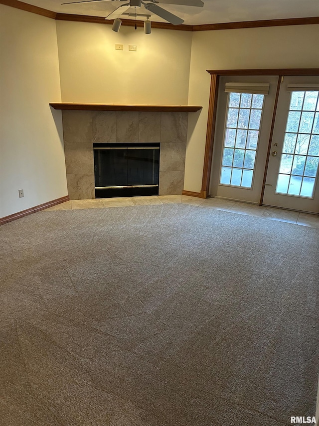 unfurnished living room with ceiling fan, ornamental molding, a tiled fireplace, and carpet flooring