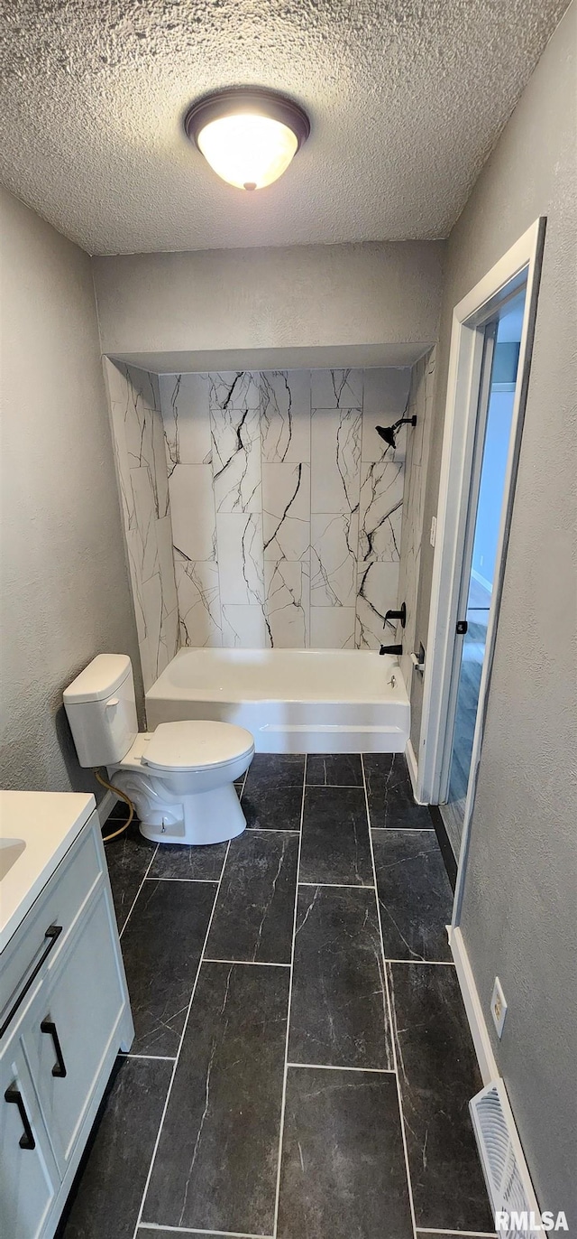 bathroom with toilet, a textured ceiling, a tile shower, and vanity