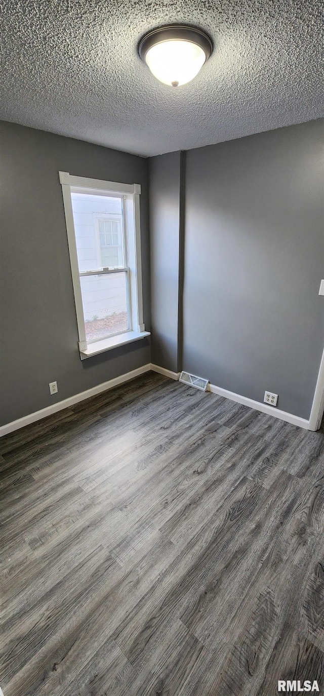 unfurnished room featuring a textured ceiling and dark hardwood / wood-style floors