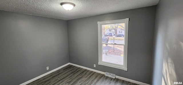 unfurnished room with a textured ceiling and dark wood-type flooring