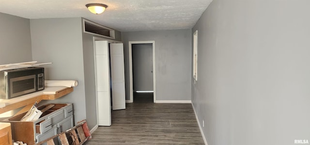 corridor featuring a textured ceiling and dark wood-type flooring