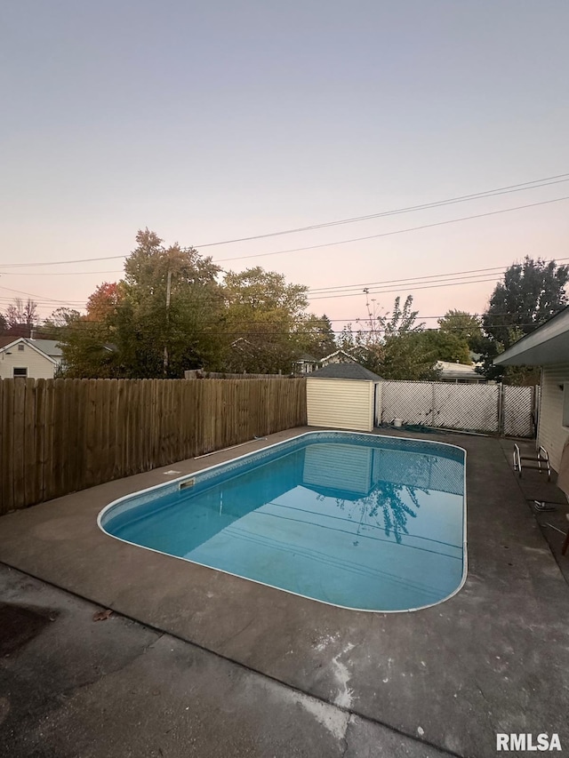 pool at dusk with a storage shed