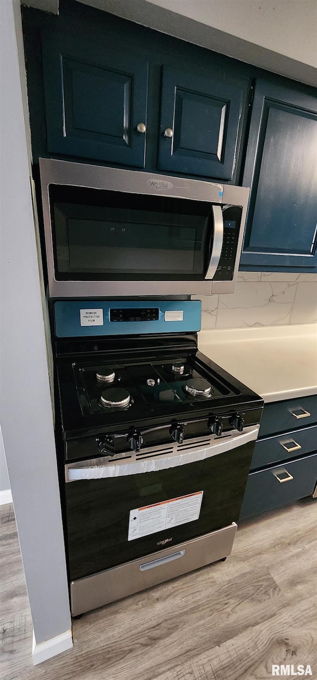 interior details featuring light hardwood / wood-style floors, stainless steel appliances, and tasteful backsplash