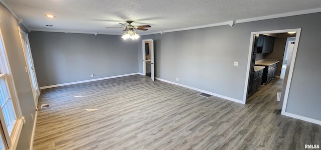 spare room with wood-type flooring, a textured ceiling, ceiling fan, and crown molding