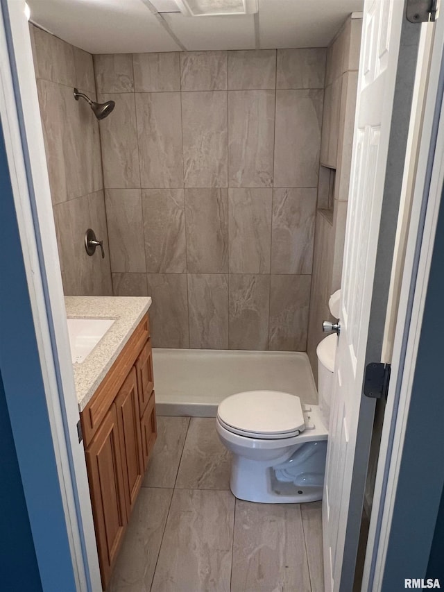 bathroom featuring vanity, toilet, and a tile shower