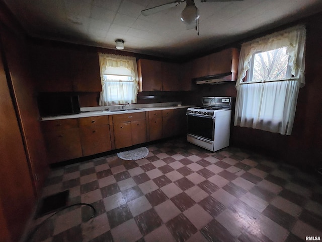 kitchen featuring ceiling fan, sink, range hood, and gas range gas stove