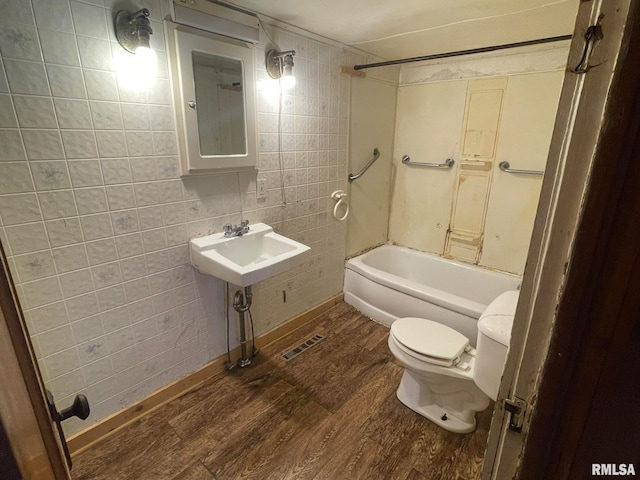 bathroom featuring hardwood / wood-style flooring,  shower combination, and tile walls