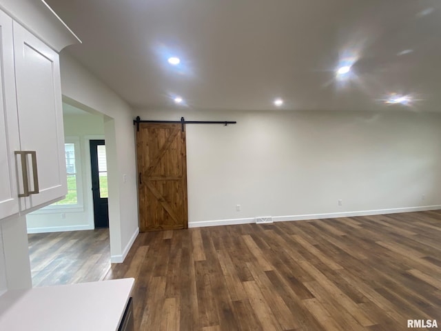 spare room featuring dark hardwood / wood-style flooring and a barn door