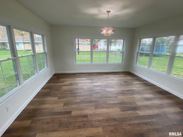 unfurnished dining area with dark wood-type flooring and an inviting chandelier