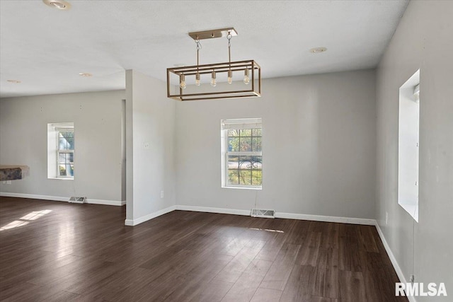 unfurnished dining area with dark hardwood / wood-style flooring and an inviting chandelier