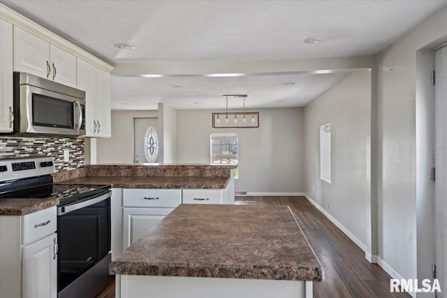 kitchen featuring white cabinetry, a center island, dark hardwood / wood-style flooring, a textured ceiling, and appliances with stainless steel finishes