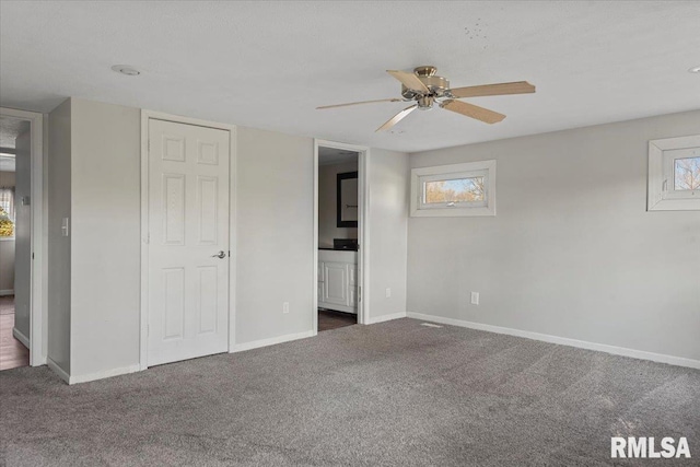 unfurnished bedroom featuring ensuite bath, ceiling fan, and dark colored carpet