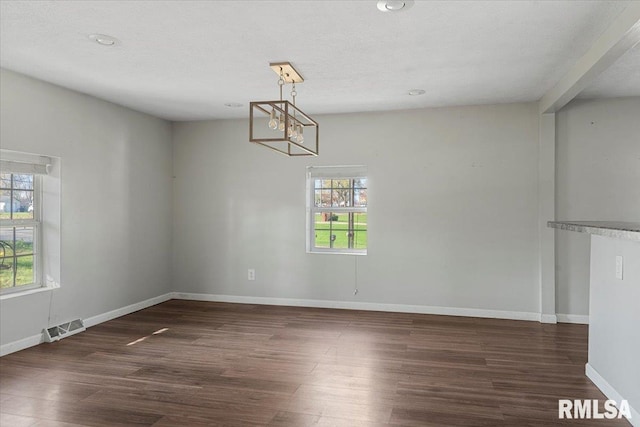 unfurnished dining area with a textured ceiling, a healthy amount of sunlight, and dark wood-type flooring